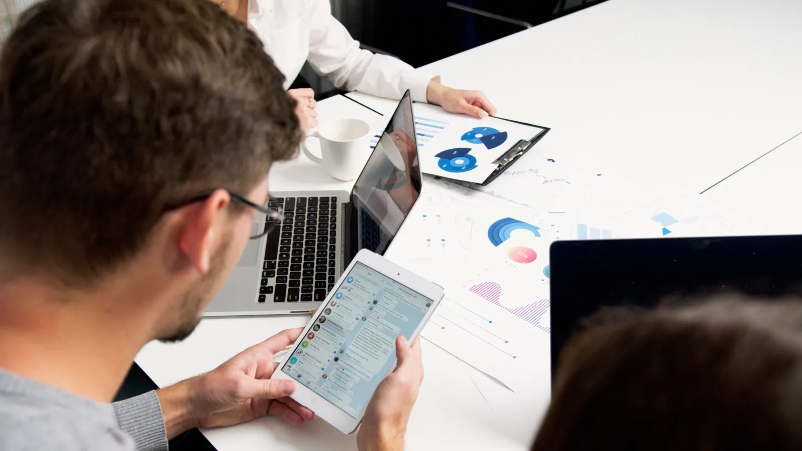 Kollegor som går igenom data och diagram tillsammans på surfplatta och laptop, som symbol för automatiserade processer